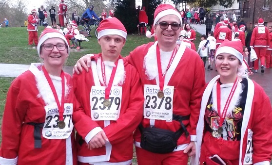 Family of four dressed as Santas wearing medals